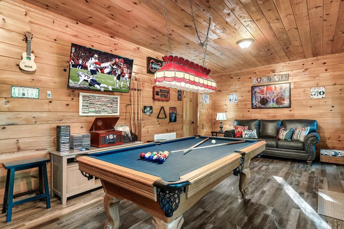 Step into the downstairs music-themed room, where classic rock signs decorate the walls, a Victrola music player and a collection of albums, cassettes,  and CDs set the vibe, while a Roku TV and pool table invite hours of entertainment