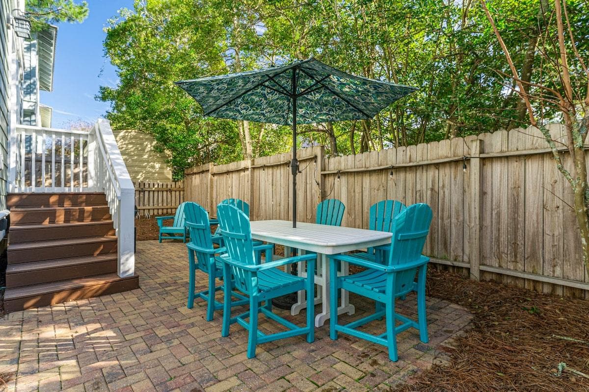 Backyard with Polywood tables, umbrella, 8 chairs, and a charcoal grill