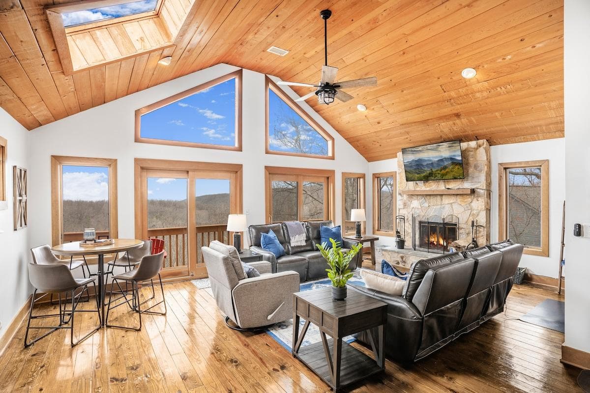 Upper level living room with 2 power reclining leather sofas, recliner, Roku TV, wood-burning fireplace, table, 4 chairs, work desk & chair, kitchenette, coffee bar, and mini fridge. The deck has 3 polywood chairs, 2 small tables, & incredible views!