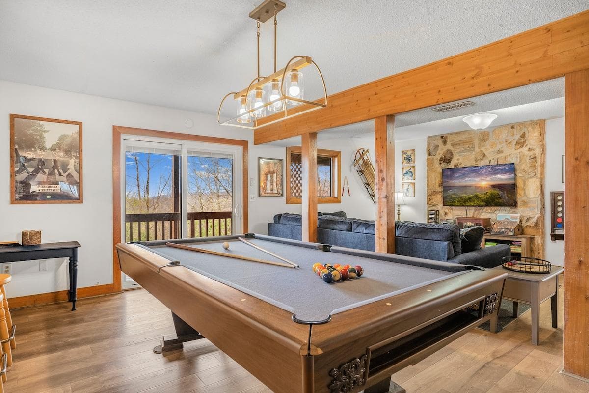 The music-themed lower level has a pool table, sectional sofa, 50" Roku TV, connect 4 game, board games with a table and 2 benches to play on, 60-in-1 multicade game, music posters on the wall, a Victrola music player w/ albums, CDs, & cassettes