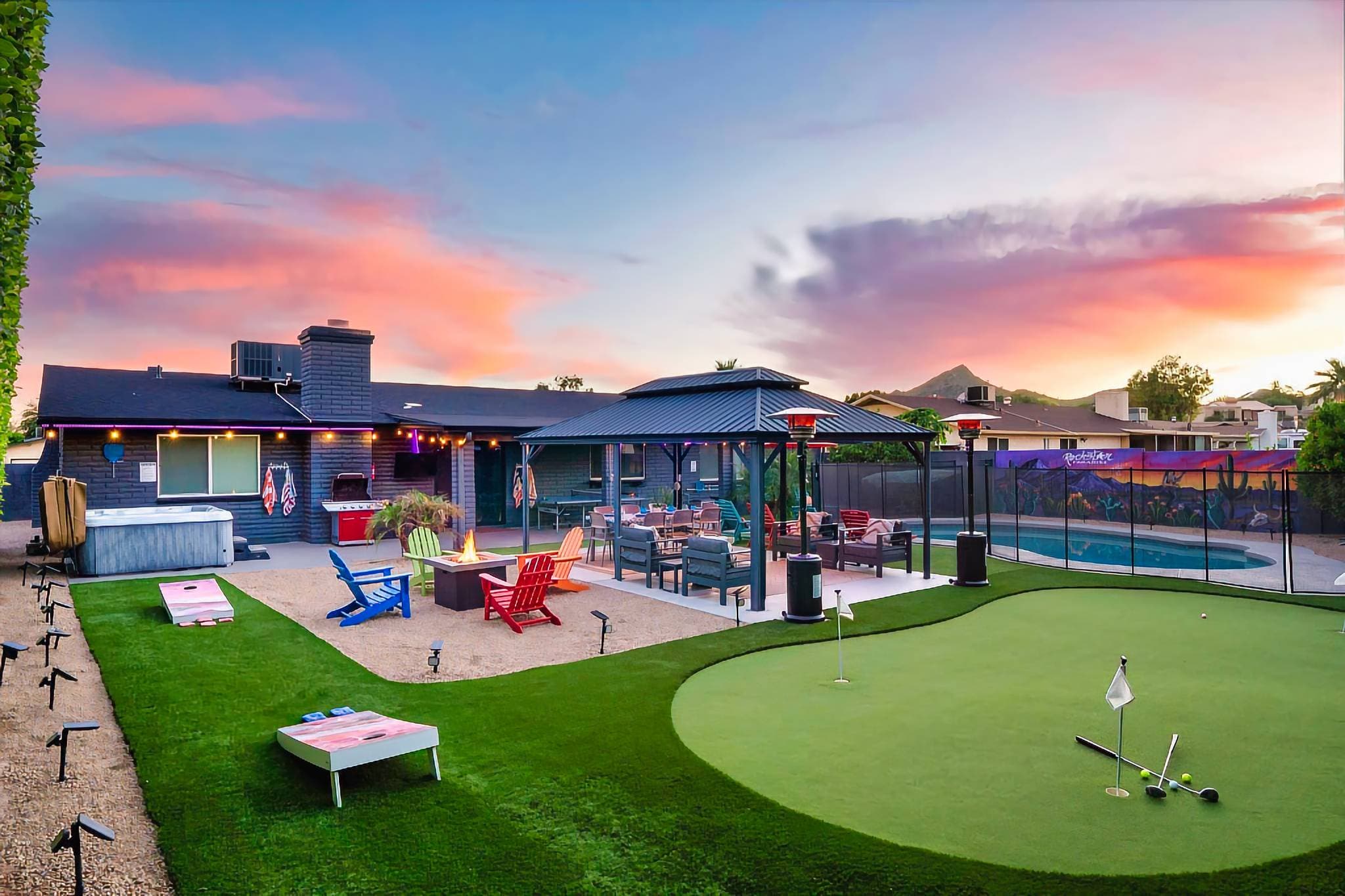 "Rockstar Paradise" backyard complete with a custom mural, hot tub, fire pit, gas grill, corn hole, 3 hole putting green, gazebo w/ outdoor dining table, 50 colored solar LED lights, patio heaters, ping pong table, and a heated pool w/ a safety gate